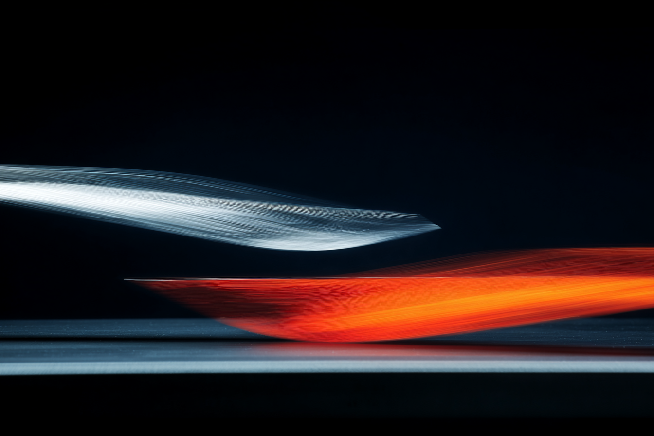 Two identical glass rods suspended in dark space — one poised still, one vibrating with blur at the tip — single lateral raking light