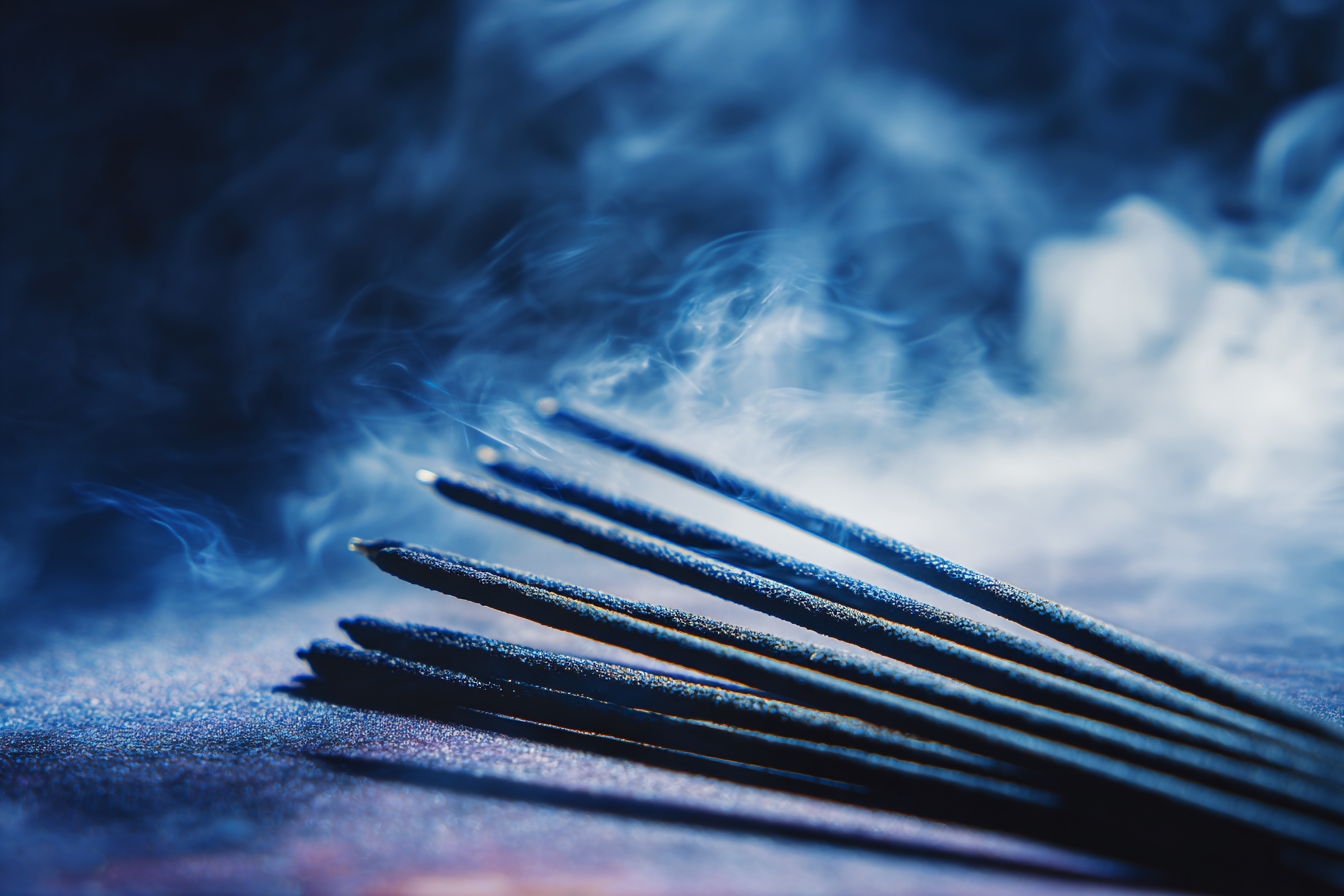 Five slender obsidian rods fanned outward from a single dark base point, each rod's tip catching a cobalt-blue spot of volumetric light at a different angle